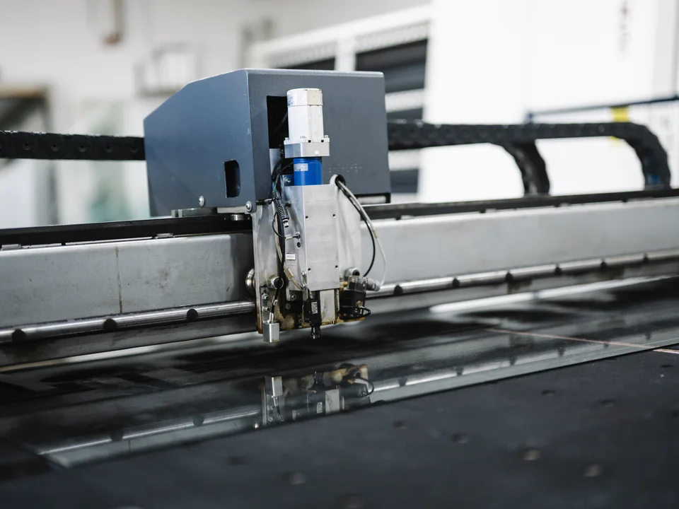 Máquina industrial de corte trabajando sobre una superficie plana; imagen de referencia no vinculada al cliente.